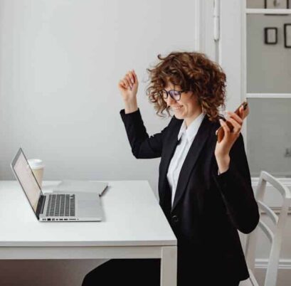 A Woman in Black Blazer Sitting in Front of the Table with Laptop