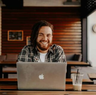 man in black and white striped polo shirt sitting on chair in front of silver macbook