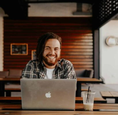 man in black and white striped polo shirt sitting on chair in front of silver macbook