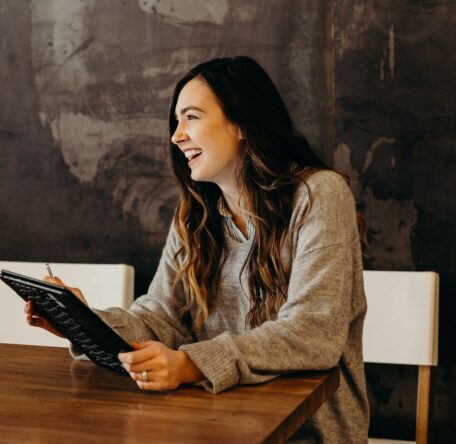 woman sitting around table holding tablet